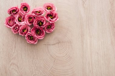 kopya alanı ile ahşap masa üzerinde pembe eustoma çiçeklerden yapılmış kalp işareti üst görünümü