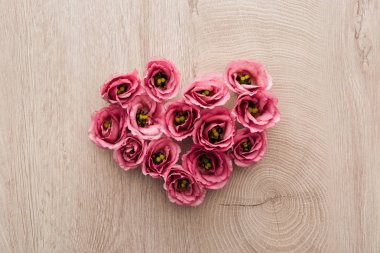 ahşap masa üzerinde pembe eustoma çiçeklerden yapılmış kalp işareti üst görünümü