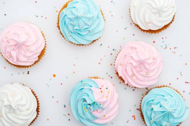 top view of delicious white, pink and blue cupcakes with sprinkles Isolated On White clipart