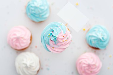 sprinkles ve boş kart Beyaz İzole ile lezzetli pembe, beyaz ve mavi cupcakes üst görünümü