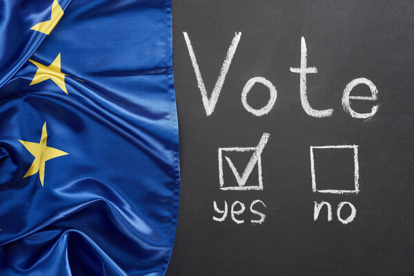 top view of vote lettering and check mark near yes word on black chalkboard near European flag