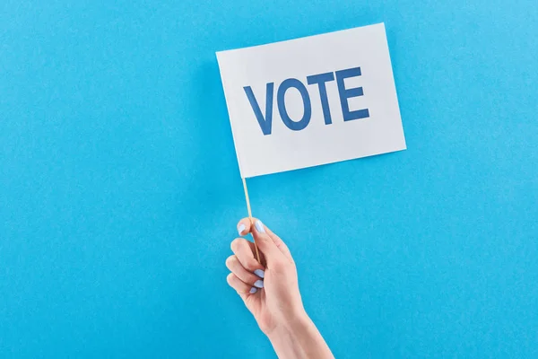 コピースペース付きの青い背景に投票文字でフラグを保持している女性のトリミングビュー — ストック写真