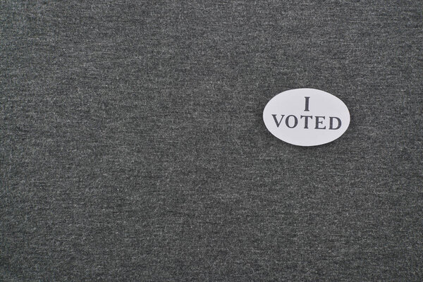 top view of badge with i voted lettering on textured background