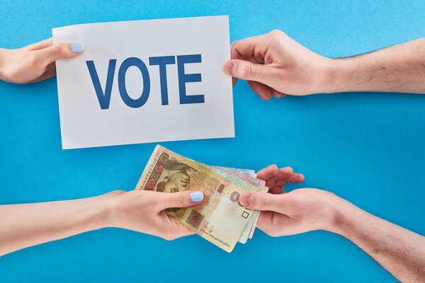 partial view of woman giving ukrainian hryvni for vote to man on blue background