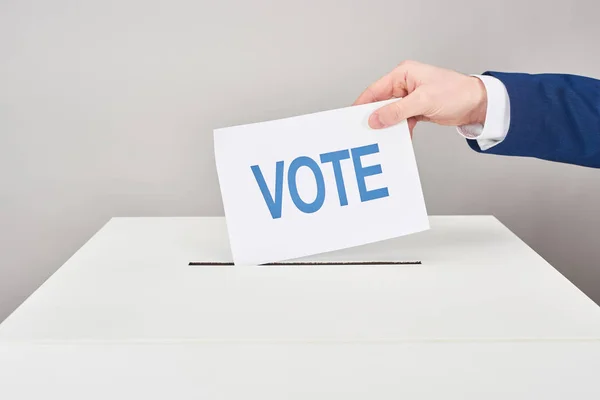 灰色の背景にボックスに投票を置く男のトリミングビュー — ストック写真
