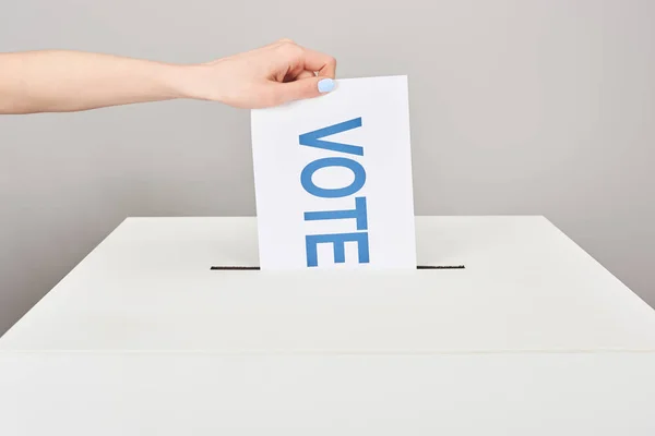 灰色で隔離された箱に投票を持つカードを置く女性のトリミングされたビュー — ストック写真