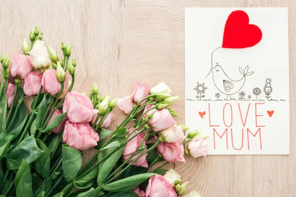 top view of pink eustoma flowers and card with love mum words on wooden table