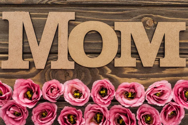 top view of pink eustoma flowers and mom word on wooden table