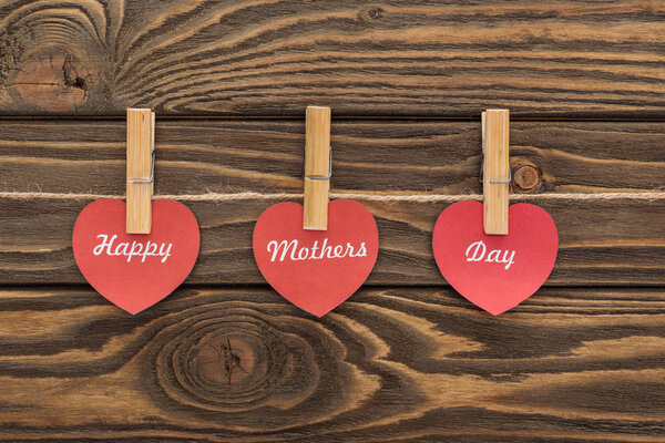 верхний вид одежды колышки и красные бумажные открытки с счастливым днем матери писать на деревянном столе
