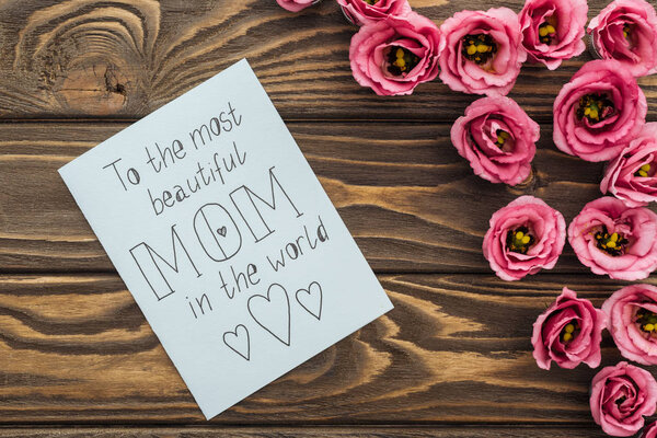 top view of eustoma flowers and card with to the most beautiful mom in the world lettering on table