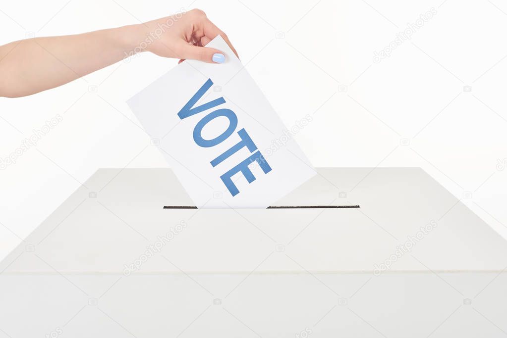 partial view of woman putting card with vote lettering in box isolated on white