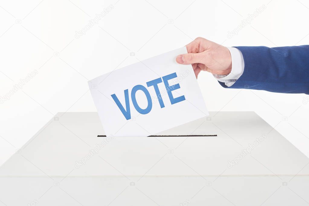 cropped view of man putting card with vote lettering in box isolated on white