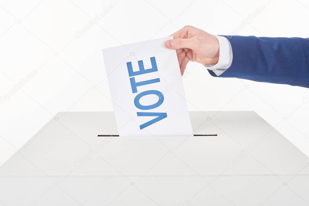 partial view of man putting card with vote lettering in box isolated on white