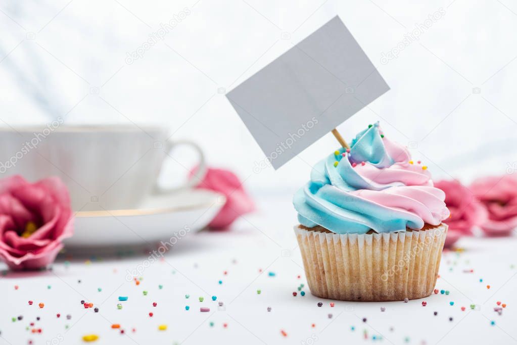 selective focus of delicious cupcake decorated with sprinkles and blank card