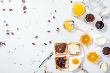 beyaz su ve portakal suyu bardak yanında tost, reçel ve kızarmış yumurta ile plaka üst görünümü