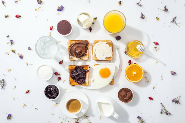 top view of tasty breakfast near glasses of water and orange juice on white
