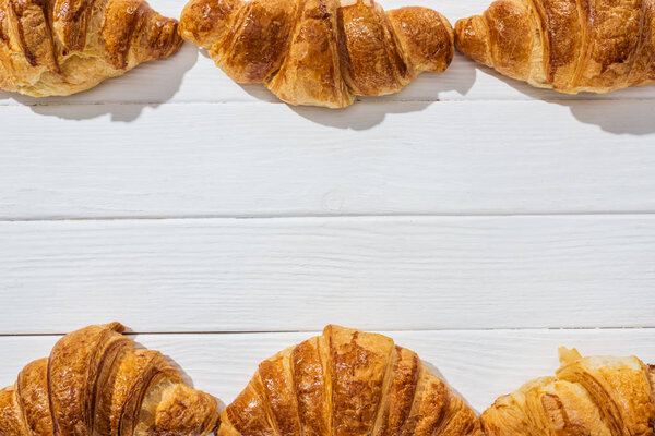 top view of tasty and sweet croissants on white wooden surface 