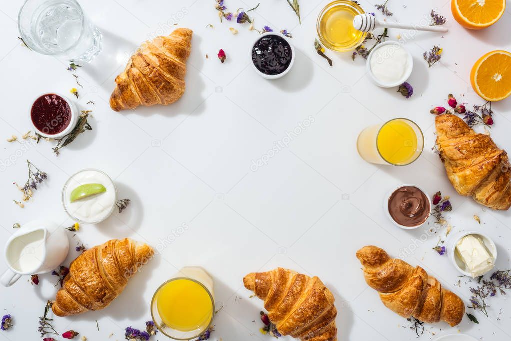 top view of tasty croissants near bowls with jam and drinks on white 