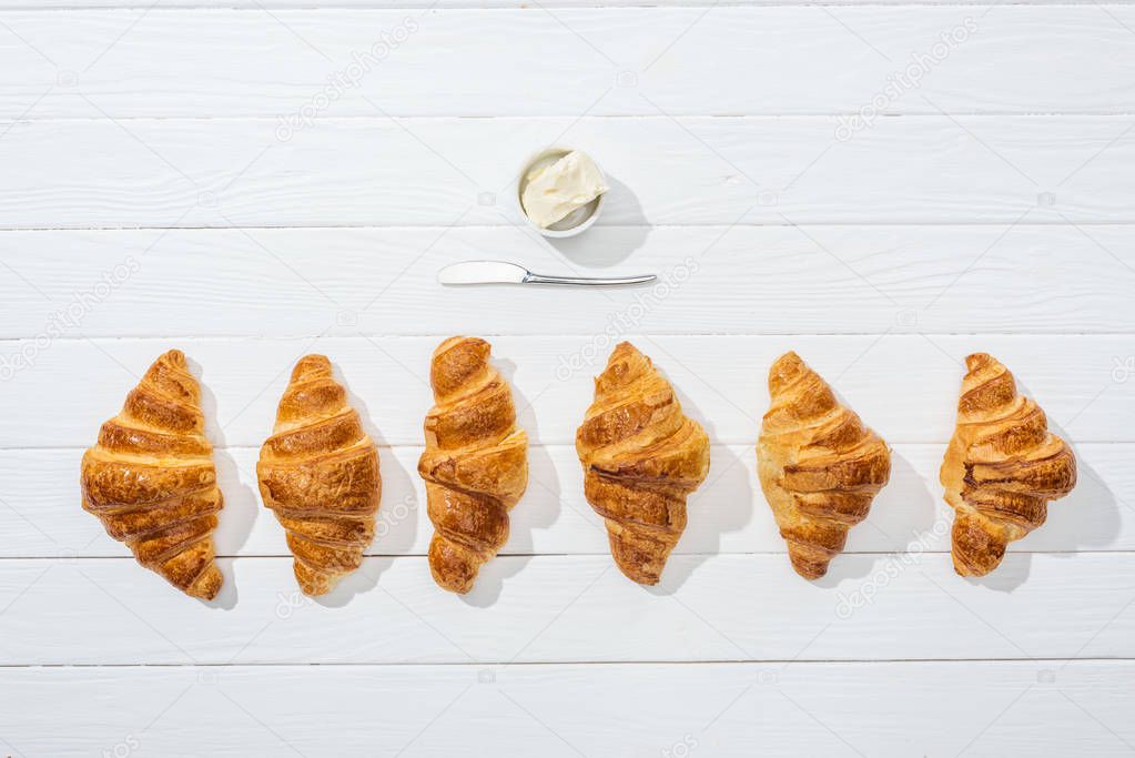 top view of knife near bowl with cream cheese and croissants on white  