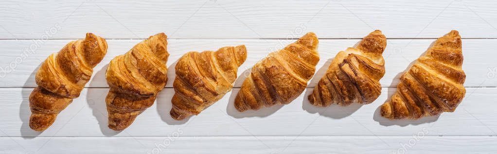 panoramic shot of golden fresh and tasty croissants on white 