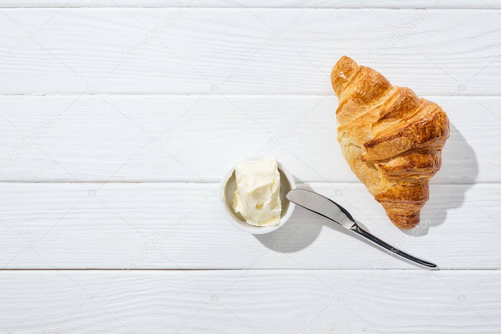 top view of knife near bowl with cream cheese and croissant on white  