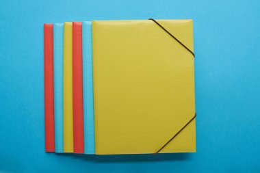 top view of red, blue and yellow paper binders on blue clipart