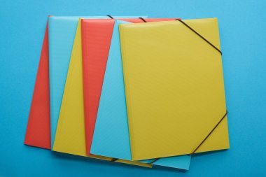top view of arranged red, blue and yellow paper binders  clipart