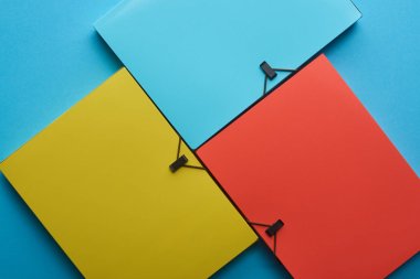 top view of arranged colorful paper folders on blue clipart