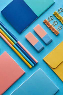 top view of notebooks and colorful stationery isolated on blue clipart