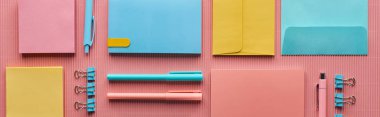 panoramic shot of various colorful stationery supplies on pink  clipart