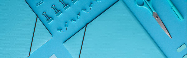 панорамный снимок бумажных связующих и различных канцелярских принадлежностей, изолированных на голубом
 