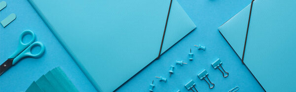 панорамный снимок бумажных связующих и различных канцелярских принадлежностей, изолированных на голубом
 