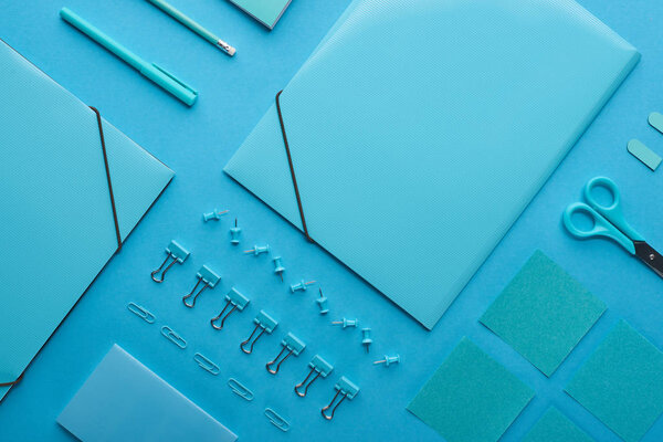 плоская укладка бумажных связок и организованных канцелярских принадлежностей, изолированных на голубом
 