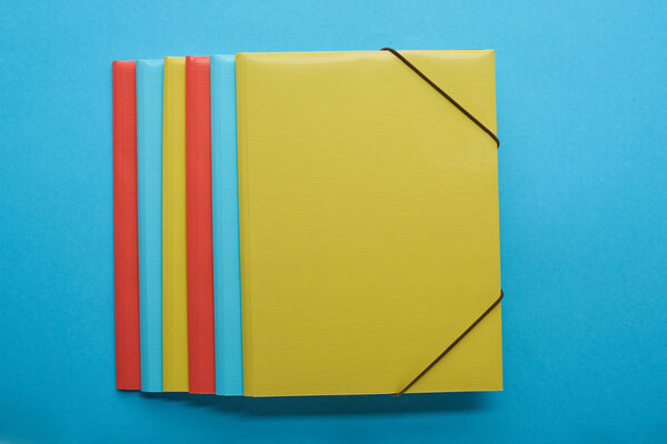 top view of red, blue and yellow paper binders on blue