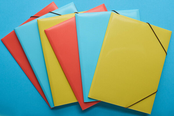 top view of multicolored office paper binders on blue