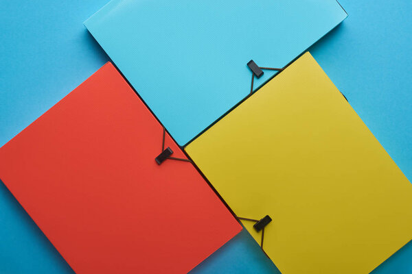 background with multicolored paper binders on blue