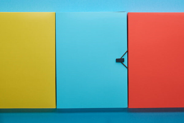 top view of colorful office paper folders on blue