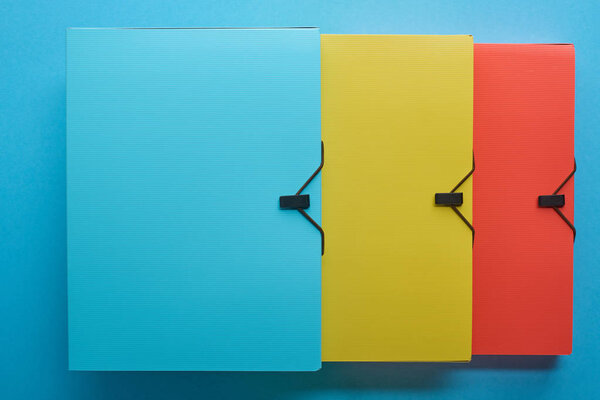 top view of colorful office paper folders on blue