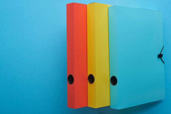 top view of colorful paper binders isolated on blue with copy space