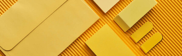 panoramic shot of sticky notes, envelope and erasers on yellow