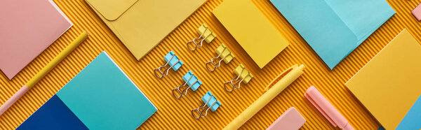panoramic shot of colorful arranged office stationery supplies on yellow