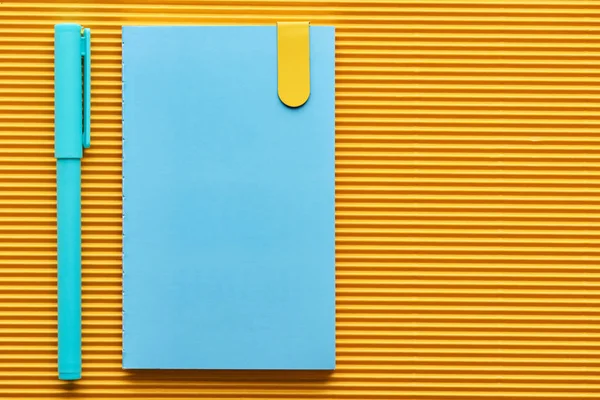 蓝色笔和笔记本的顶视图在黄色与复制空间 — 图库照片