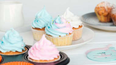 delicious cupcakes decorated with colorful frosting on plate isolated on grey clipart