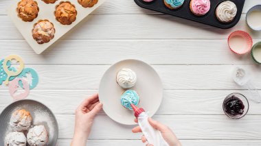 cupcake tepsileri ile masada buzlanma torbası ile kadın dekorasyon cupcakes kısmi görünümü