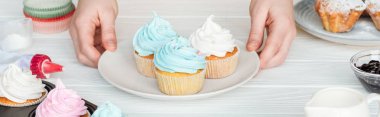 ahşap masada lezzetli cupcakes plaka tutan kadın panoramik çekim