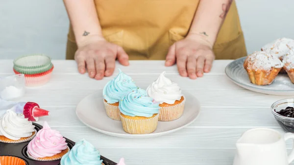 Vista Cortada Mulher Perto Mesa Com Prato Com Cupcakes Saborosos — Fotografia de Stock