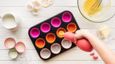masada cupcake tavada sıvı hamur döken kadın kırpılmış görünümü