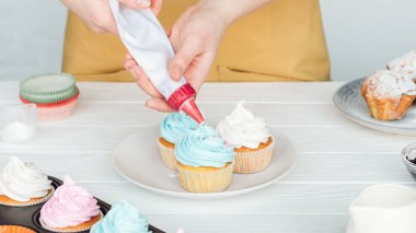 krema çantası ile kadın dekorasyon cupcakes kısmi görünümü