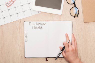 cropped view of recruiter holding pen near notebook with exit interview checklist lettering clipart