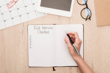 partial view of recruiter holding pen near notebook with exit interview checklist lettering clipart